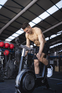 Motivated male athlete exercising on exercise bike in gym