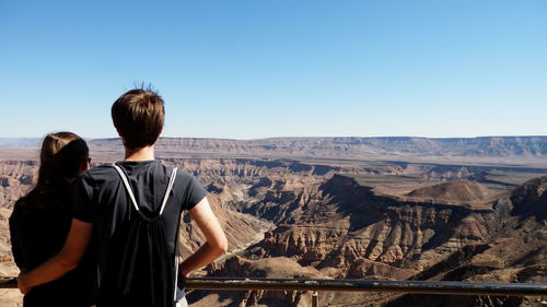 Rear view of people looking at valley against clear sky