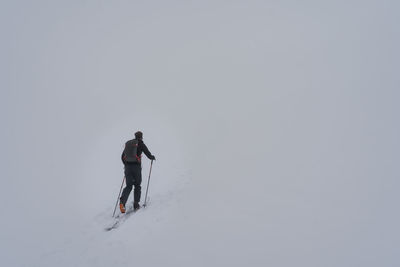 Man skiing on snowcapped mountain against clear sky