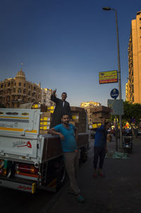 People standing on street in city against clear sky