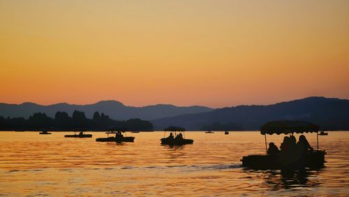 Silhouette people on river against clear sky during sunset