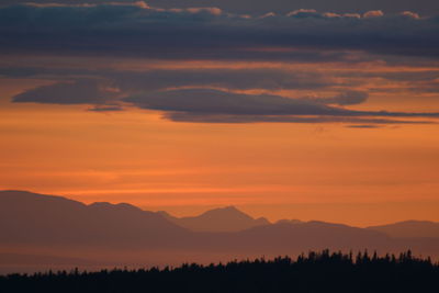 Scenic view of silhouette mountains against orange sky