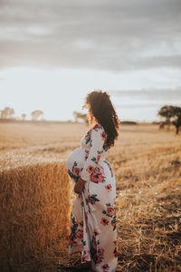 Side view of pregnant woman standing on agricultural field