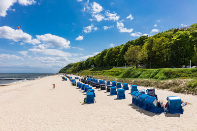 Hooded chairs at beach against blue sky