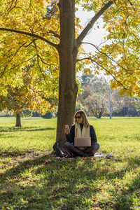 Woman sitting on field at park during autumn