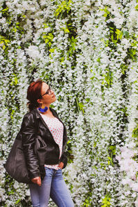 Side view of woman standing by flowers