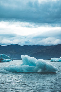 Scenic view of glaciers in sea against mountains