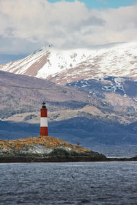 Lighthouse by sea against sky during winter