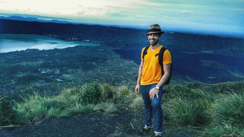 Portrait of young man standing on landscape against sky