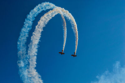 Low angle view of airplane flying against blue sky