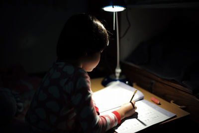 Side view of boy studying at night