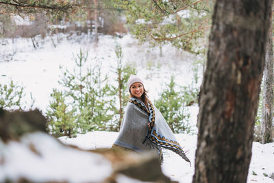 Portrait of young woman against tree trunk