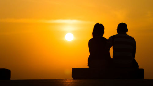 Silhouette couple against sea during sunset