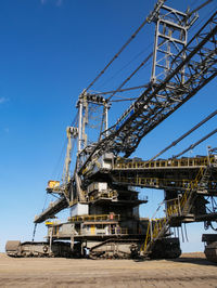 Low angle view of crane against clear blue sky