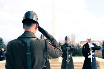 Rear view of people standing against sky