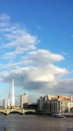 City at waterfront against cloudy sky