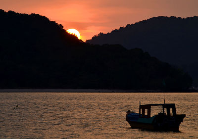 Boat sailing in sea against sky during sunset