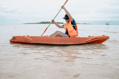 Woman sitting on boat in sea against sky