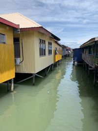 Houses by canal against sky