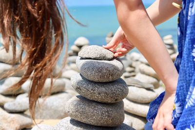 Close-up of young woman stacking rocks