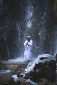 Rear view of woman standing by waterfall