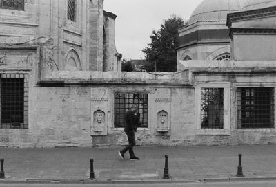 Side view of man walking on sidewalk in city