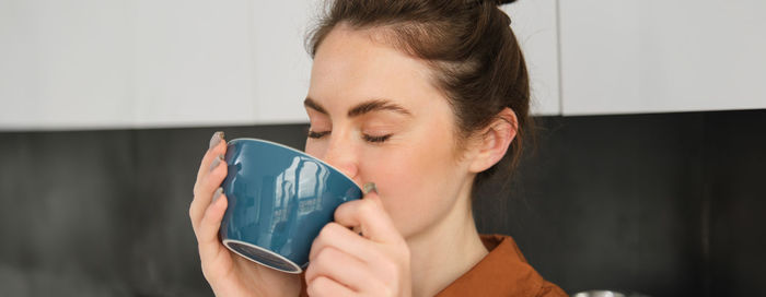 Side view of young woman drinking coffee at home