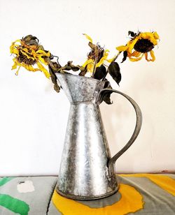 Close-up of yellow flower vase on table against wall