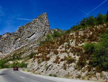 Road by rocky mountains against sky