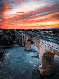 Bridge over river against sky during sunset