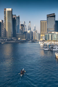 Boat in sea against modern buildings in city