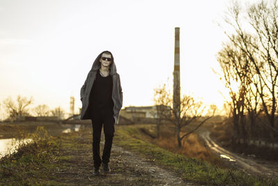 Full length portrait of walking young man in sunset