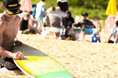 Shirtless man with surfboard at beach