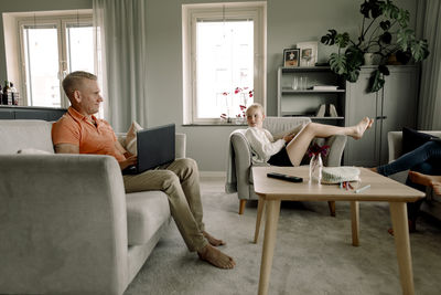 Full length of father and daughter looking at each other in living room