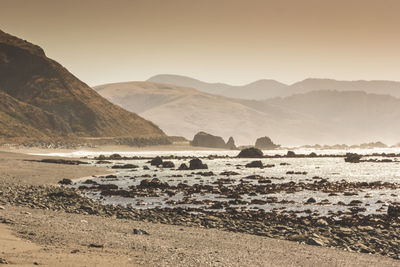 Scenic view of sea and mountains against clear sky
