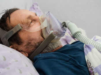 Male patient with oxygen mask lying on bed