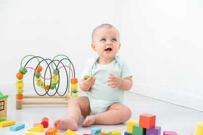 Portrait of cute baby boy playing with toy blocks against white background