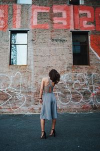 Rear view of woman standing against brick wall