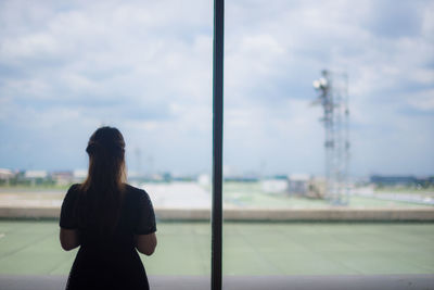 Rear view of woman standing against sky