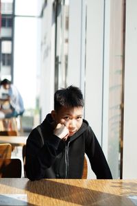 Portrait of young man sitting at table in cafe