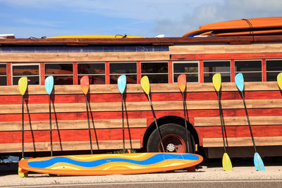 Colorful kayak and paddleboard paddles leaning against a woody style hippy bus in nassau, bahamas.