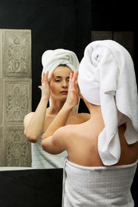 Young woman reflecting on mirror in bathroom