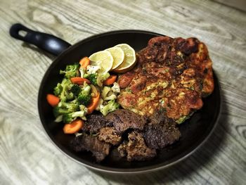 High angle view of food served in frying pan on wooden table