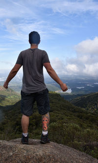 Rear view of man looking at mountain against sky