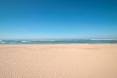 Scenic view of beach against clear blue sky