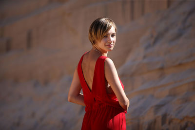 Young woman standing against red wall