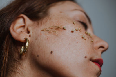 Close-up of woman with dried flowers on face