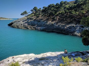 Man on rock by sea against mountain