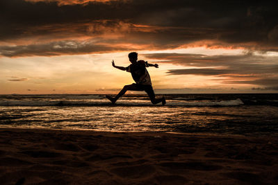 Silhouette man on beach against sky during sunset