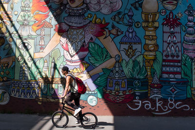 Woman riding bicycle on graffiti wall